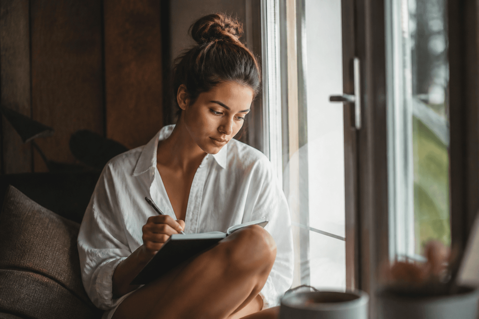 A person journaling a reflection by a window